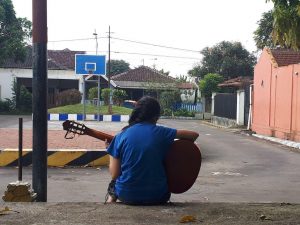 Gadis yang Bermain Gitar di Balik Punggungnya